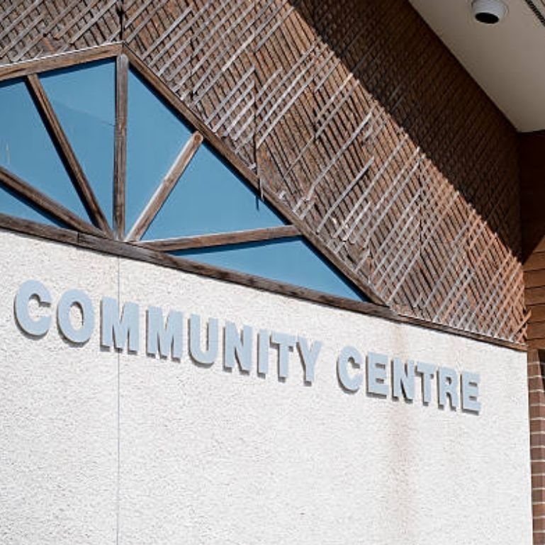 A community center building with a wooden facade and a colorful geometric pattern above the entrance