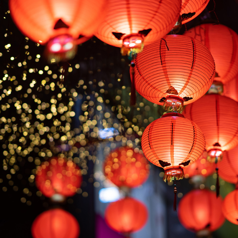 Close-up of glowing red Chinese lanterns with gold tassels, creating a festive atmosphere