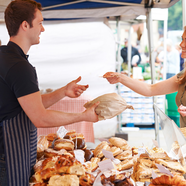 A customer buying bread from a bakery stall