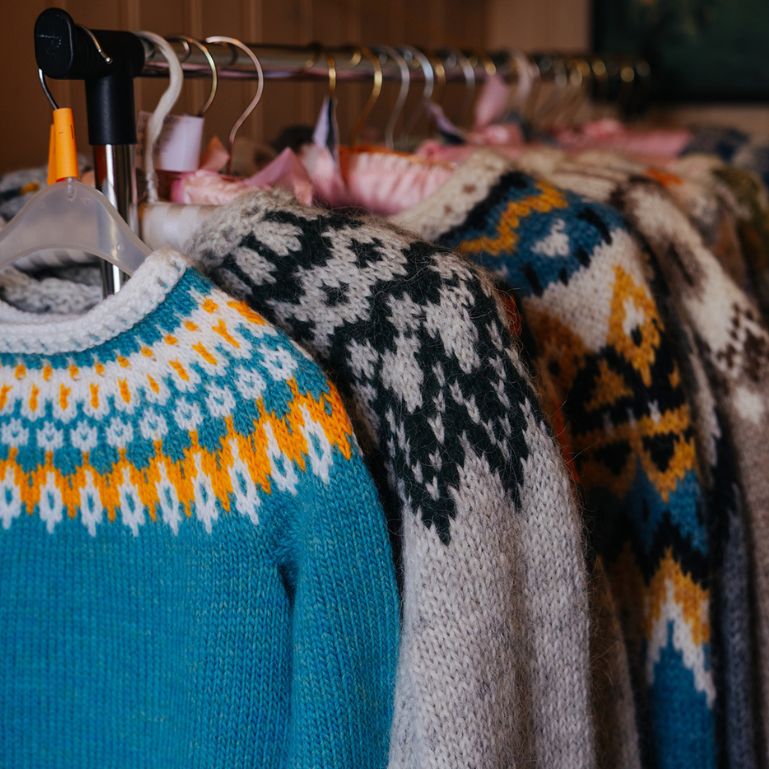 A rack of colorful knitted sweaters with intricate patterns