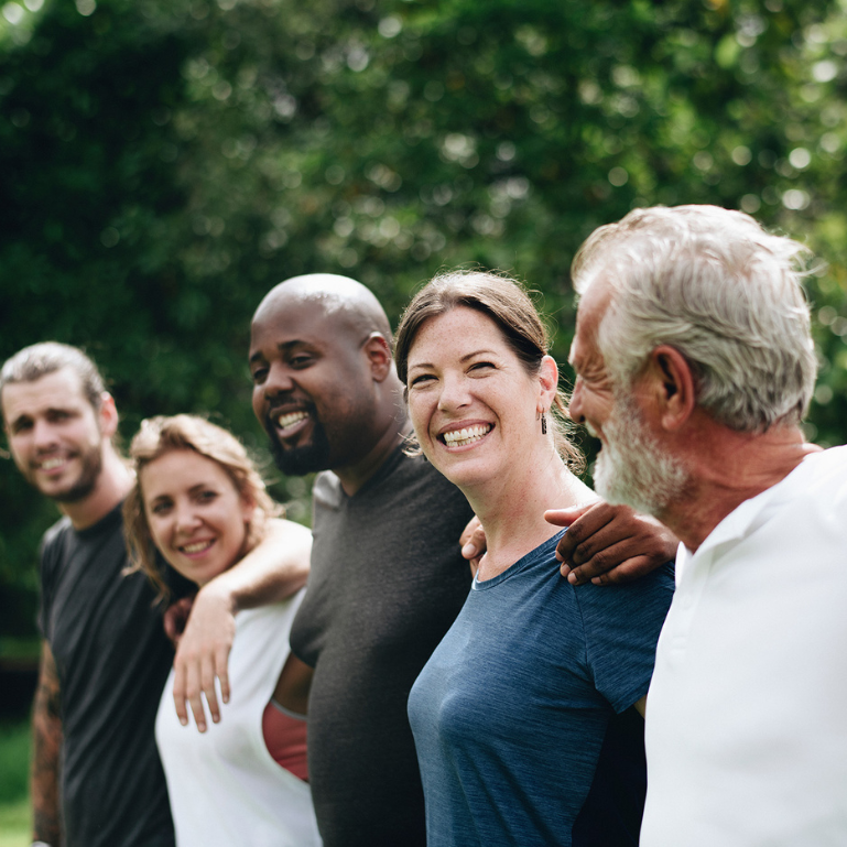 A joyful group of people holding each other and smiling, representing unity and togetherness